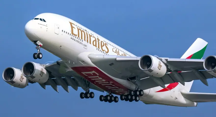Airbus A380 Emirates z wieloma miejscami na pokładzie, wznoszący się na błękitne niebo.