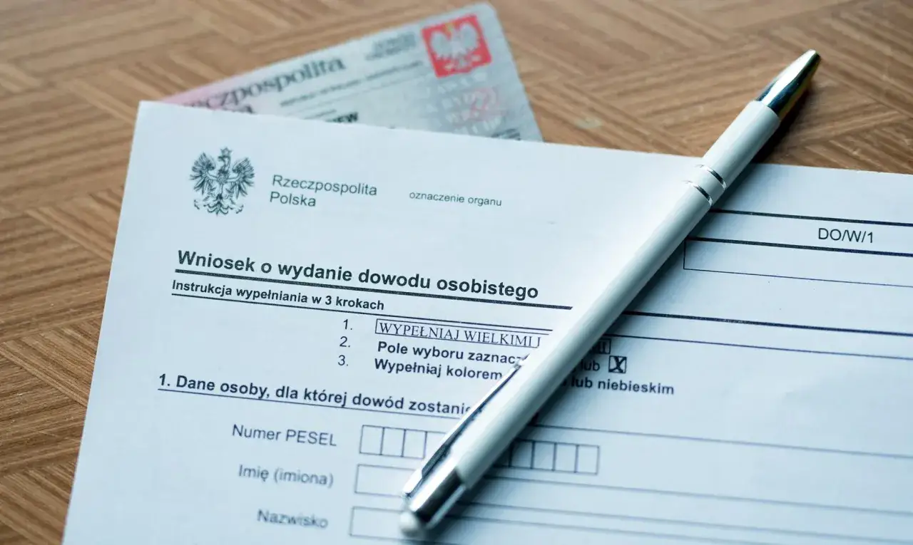 Wniosek o wydanie dowodu osobistego leży na drewnianym blacie, obok długopis. To ważny krok w procesie wymiany dowodu osobistego.