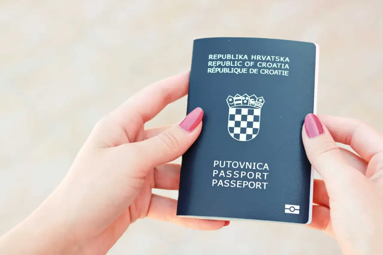 Dwie dłonie trzymają paszport Republiki Chorwacji. Czy do Chorwacji potrzebny jest paszport? Tak, ten dokument jest niezbędny do podróży.
